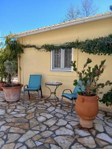 a patio with two chairs and a table and some plants at Ioana Sea View in Corfu