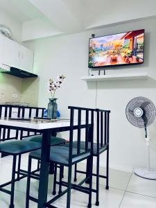 a dining room table with chairs and a tv on the wall at NagaCityRiverView 2BR Apartment in Naga