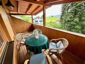 a porch with a green table and chairs on it at Rosi's Ferienwohnung Kampenwandblick in Prien am Chiemsee