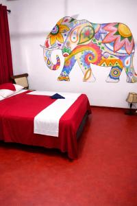 a bedroom with a bed with a painting of an elephant at Solar House Hotel in Dickwella