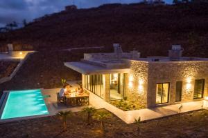 a man sitting at a table in front of a house at Sea view villa with private swimming pool in Heraklio