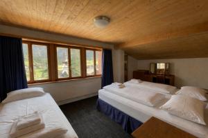 a bedroom with two beds and a large window at Chalet Rosa B&B in Lauterbrunnen
