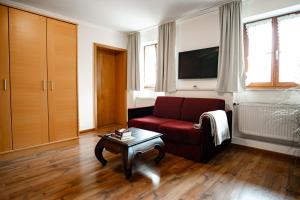 a living room with a red couch and a coffee table at Ferienwohnungen Steinbacher in Vogtareuth