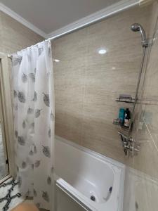 a bathroom with a shower curtain and a bath tub at Olmazor Comfort in Qoraqamish +8 photos
