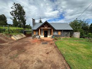 a small house in a field with a yard at The T Cottage in Othaya