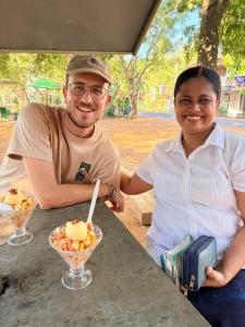 a man and a woman sitting at a table with a bowl of fruit at Abha Sewana අඹ සෙවණ in Anuradhapura