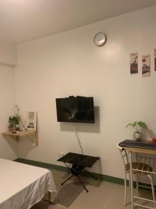 a room with a tv on a wall with a table at Bright Nook in Manila