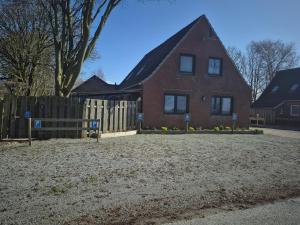 a red brick house with a wooden fence at Apartmenthaus Westerkoog in Hedwigenkoog