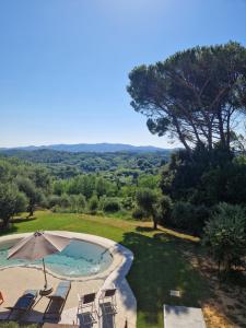 an outdoor swimming pool with an umbrella and chairs at Casa Lori in Fauglia