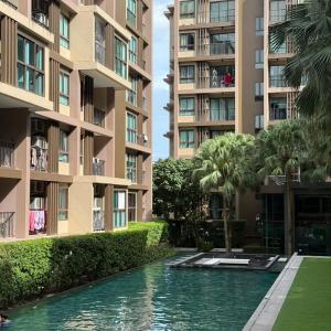 a swimming pool in front of a building with palm trees at Zcape garden by lsqstays in Ban Rangeng