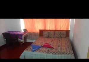 ein Schlafzimmer mit einem Bett mit rotem Vorhang und einem Tisch in der Unterkunft Hotel refresh in Moratuwa