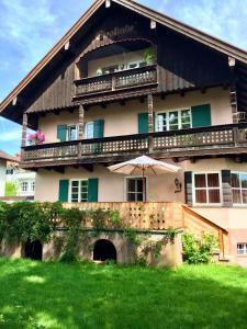 a large house with a balcony with an umbrella at Rosi's Ferienwohnung im Haus Sieglinde in Prien am Chiemsee