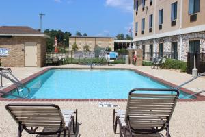 a swimming pool with two lawn chairs next to a building at Holiday Inn Express Hotel & Suites Center by IHG in Center