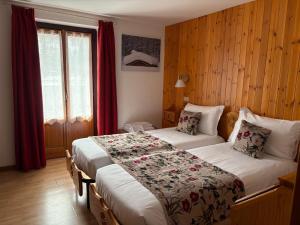 two beds in a hotel room with red curtains at Hotel Col Serena in Etroubles