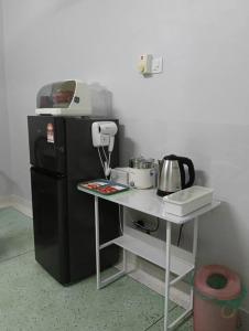 a small kitchen with a table and a black refrigerator at Aplus Homestay Kluang A嘉民宿 in Kluang