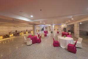 a banquet hall with white tables and red chairs at Hotel Krishnam Vrindavan in Vrindāvan