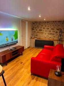 a living room with a red couch and a flat screen tv at Gîte de Charme in Saint-Avit-de-Tardes