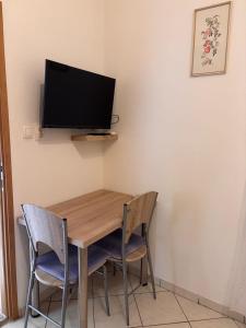 a dining room table with two chairs and a tv on the wall at Nadalina 10 in Starigrad