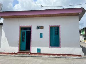 a small white building with green doors on a street at Casa Samuel in Honda +7 photos