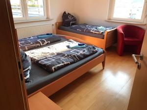 two beds in a room with a red chair at Bimbacher Betten in Bimbach