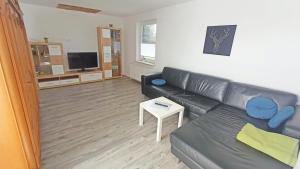 a living room with a black leather couch and a table at Fenland Mill Ranch in Wolthausen