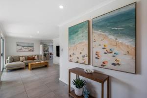 a living room with two large paintings of a beach at Mooloolaba Canal Retreat with Pool Sleeps 12 in Mooloolaba