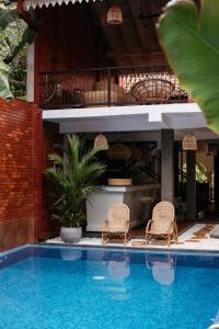 two wicker chairs sitting next to a swimming pool at Roots Retreat in Unawatuna