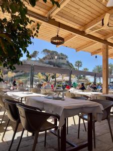 a restaurant with tables and chairs under a wooden roof at Hotel Playa San Cristóbal in Almuñécar