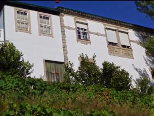 um antigo edifício branco com janelas e arbustos em Quinta do Fôjo em Lamego