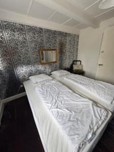 a large white bed in a bedroom with a wall at Skelby Præstegård lej 2 in Gedser
