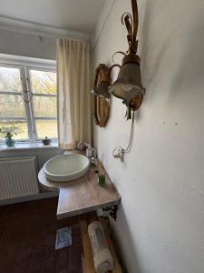 a bathroom with a sink and a lamp on the wall at Skelby Præstegård lej 2 in Gedser +8 photos