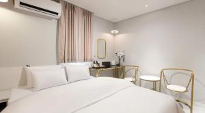 a bedroom with a white bed and a mirror at 아티초크 호텔 in Kajŏng-dong