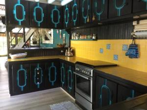 a kitchen with black cabinets and turquoise at Fare Haurevaiti Moorea in Paopao