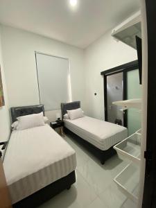 two beds in a room with white walls at Kampung Febri Resort in Cibuntu