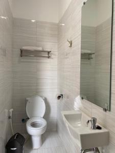a white bathroom with a toilet and a sink at Kampung Febri Resort in Cibuntu