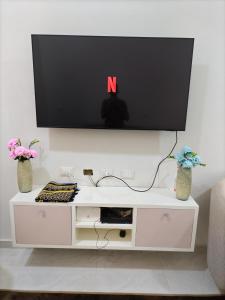 a white entertainment center with a flat screen tv on a wall at realistic country guest house in Al Aqālitah
