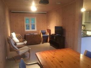 a living room with a table and chairs and a television at Konstali Gard in Flekkefjord