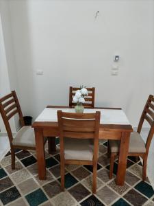 a dining room table with two chairs and a vase of flowers at realistic country guest house in Al Aqālitah