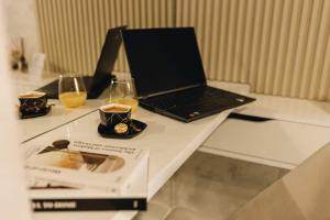 a laptop on a table with two glasses and a book at Apartman Prime - free parking in Belgrade
