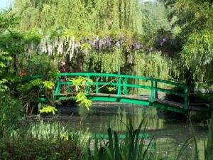 a green bridge over a pond in a garden at La mésAnges in Giverny +5 photos