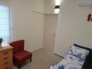 a bedroom with a bed and a chair and a door at The Pearl in Sha‘alvim