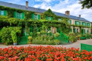 a building covered in ivy with flowers in front of it at La mésAnges in Giverny