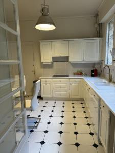 a kitchen with white cabinets and a black and white tile floor at Erawan Boutique Hôtel in Évreux