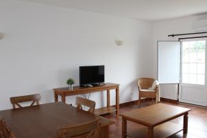 a living room with a table and a tv and chairs at Casas de Miróbriga in Santiago do Cacém