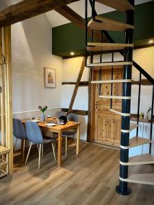 a dining room with a wooden table and a spiral staircase at Ferienhaus Schwalmblick in Schwalmstadt +12 photos