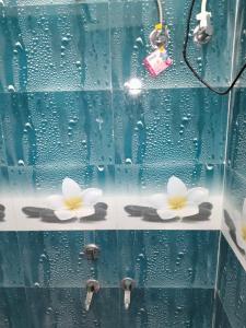 two white flowers on a glass shower stall at Hotel Maa Bhagvati in Orchha