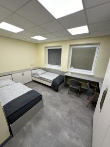 a room with two beds and a desk and two windows at Fully Equipped Guest House Košice-Barca in Košice