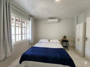 a bedroom with a large bed with a blue blanket at BC Bier Hostel in Balneário Camboriú