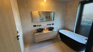 a bathroom with a tub and a sink and a mirror at Executive Villa with pool in Londerzeel