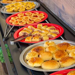 four trays of pastries on a counter with plates at Pousada Grande Rio in Pirapora
